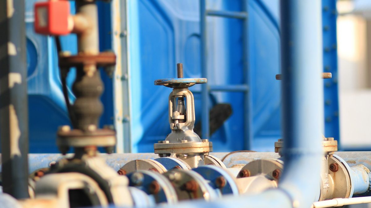 Blue industrial piping with flanged joints and an isolation valve in a plant