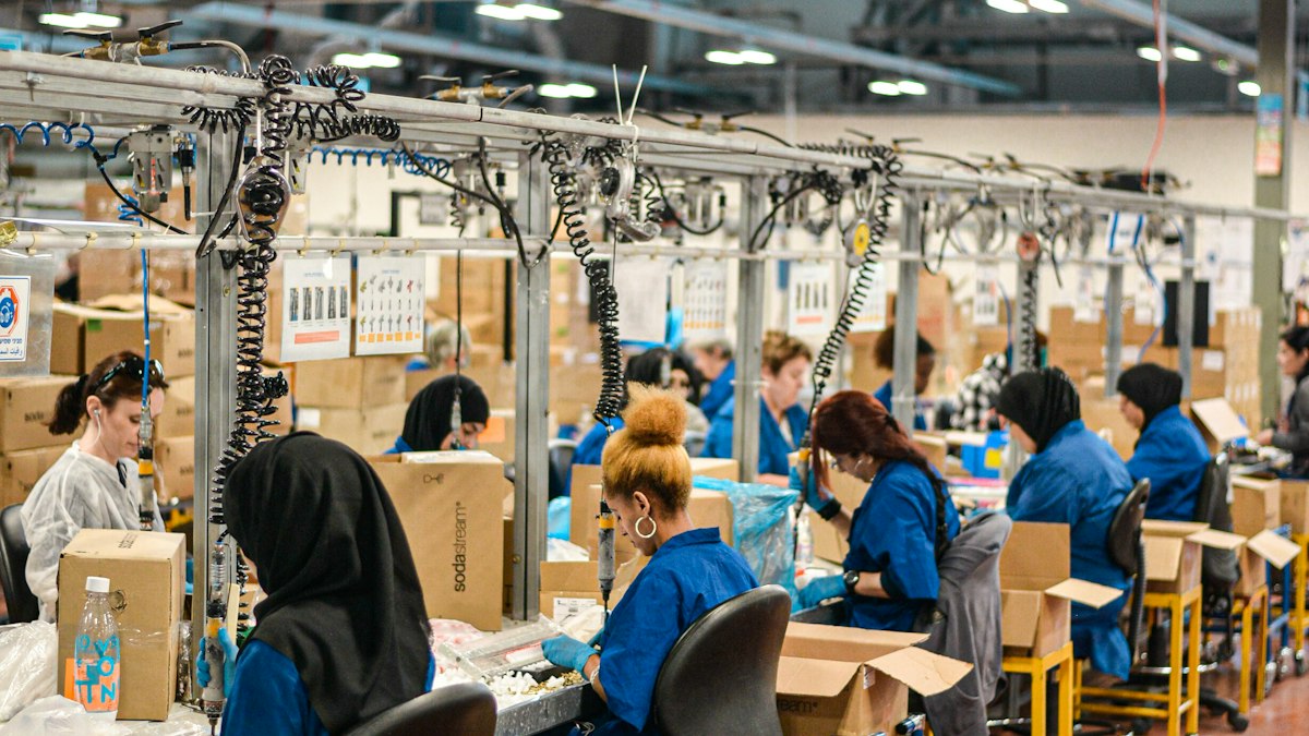 Workers in blue uniforms at an assembly line in a large factory