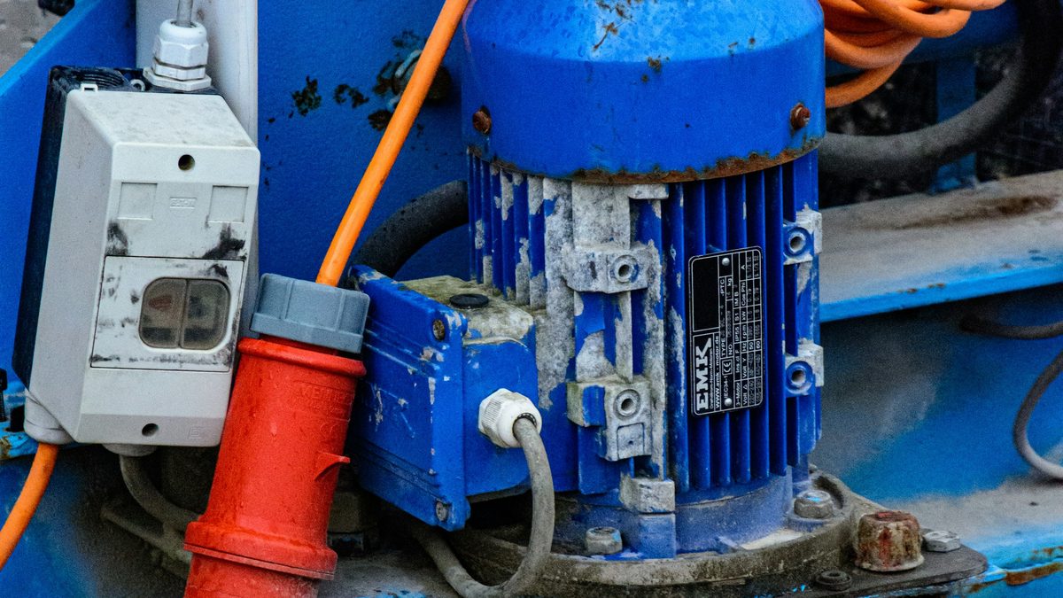 Close-up of a blue industrial electric motor with power cabling