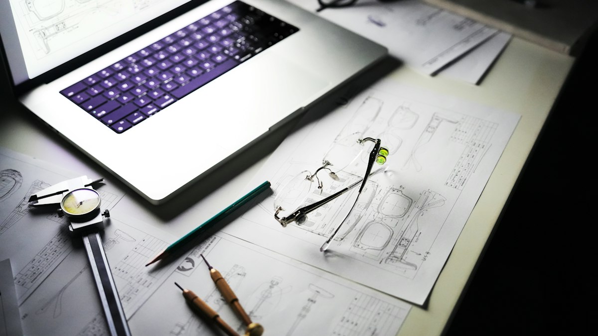 Desk with a laptop, blueprints and tools laid out for project planning
