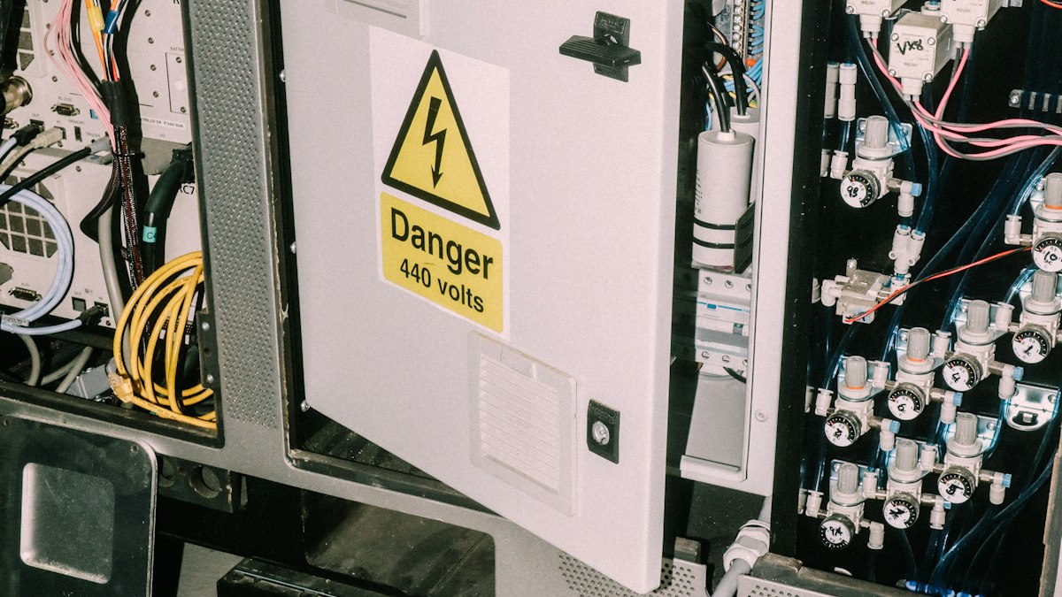 Open industrial electrical panel with wiring and a high voltage warning label