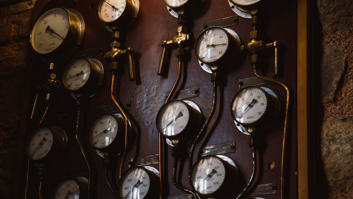 A wall of analog pressure gauges with brass valves and tubing